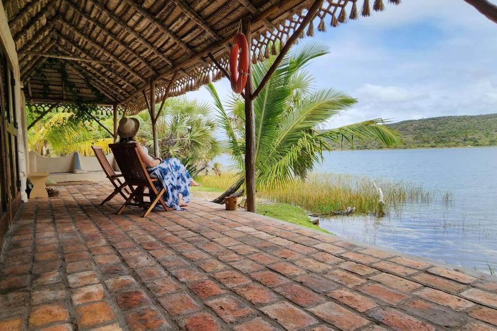 Lakeside Paradise Inhambane في Ligogo: امرأة جالسة على كرسي بجوار جسم من الماء