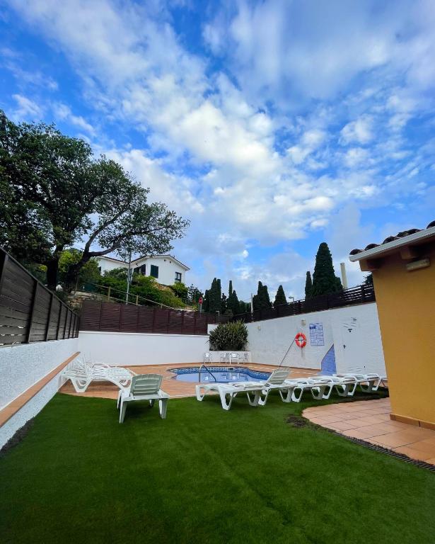 a patio with two white benches in a yard at Hotel Turissa in Tossa de Mar