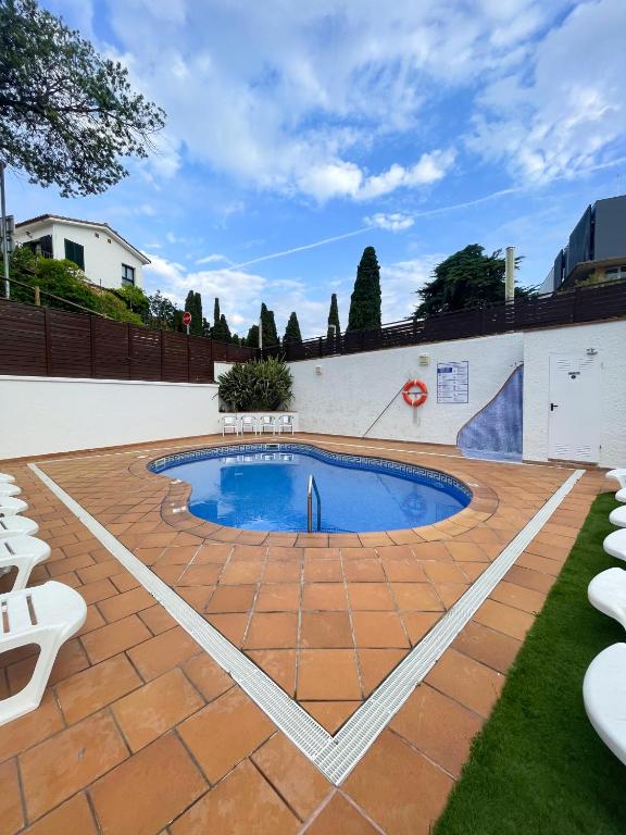 a swimming pool on a brick patio with chairs at Hotel Turissa in Tossa de Mar