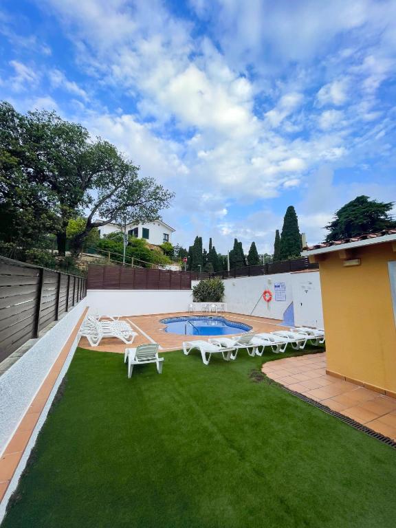 a backyard with a pool and chairs and grass at Hotel Turissa in Tossa de Mar