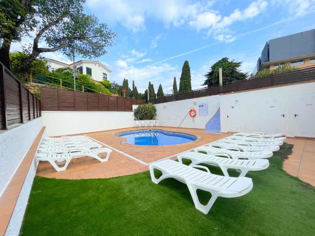 a group of white lounge chairs sitting on the grass at Hotel Turissa in Tossa de Mar