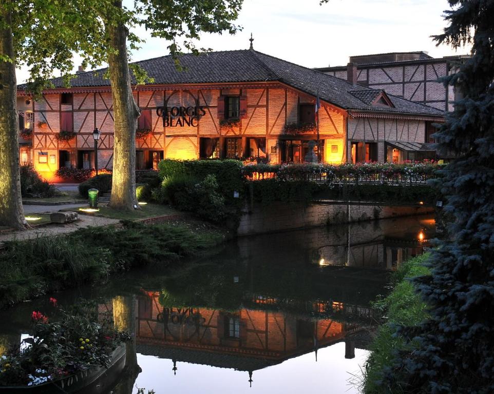 a building next to a river in front of a building at Georges Blanc Parc & Spa in Vonnas