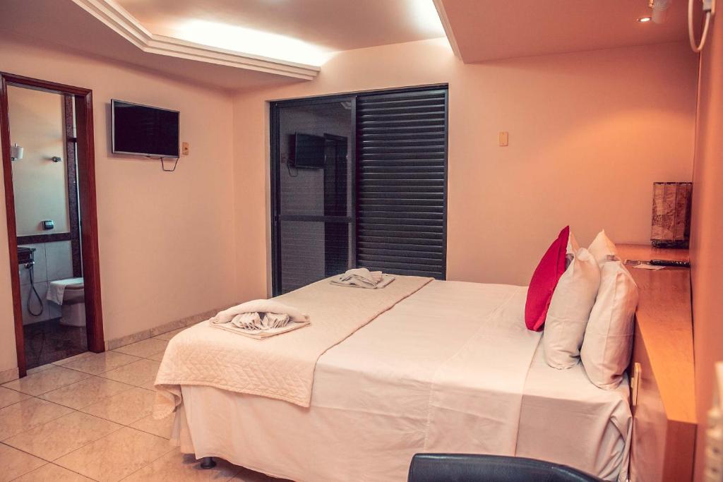 ein Schlafzimmer mit einem großen weißen Bett und ein Badezimmer in der Unterkunft STALO HOTEL in Piuí