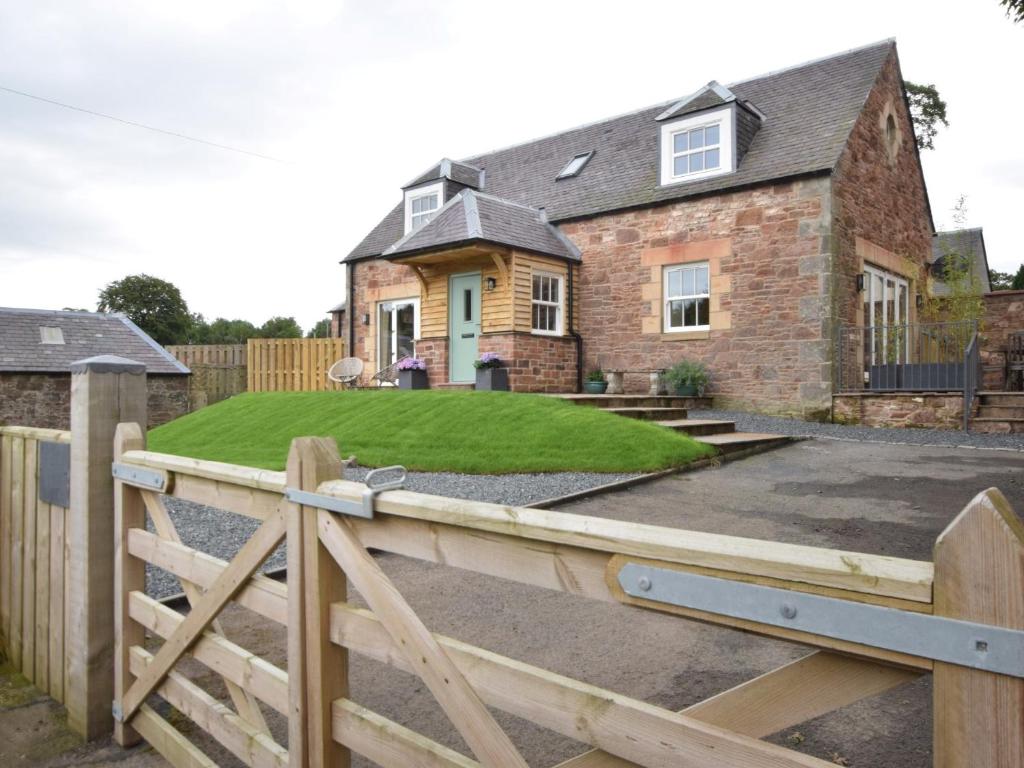 a house with a wooden fence and a yard at 2 Bed in Peebles 76383 in West Linton