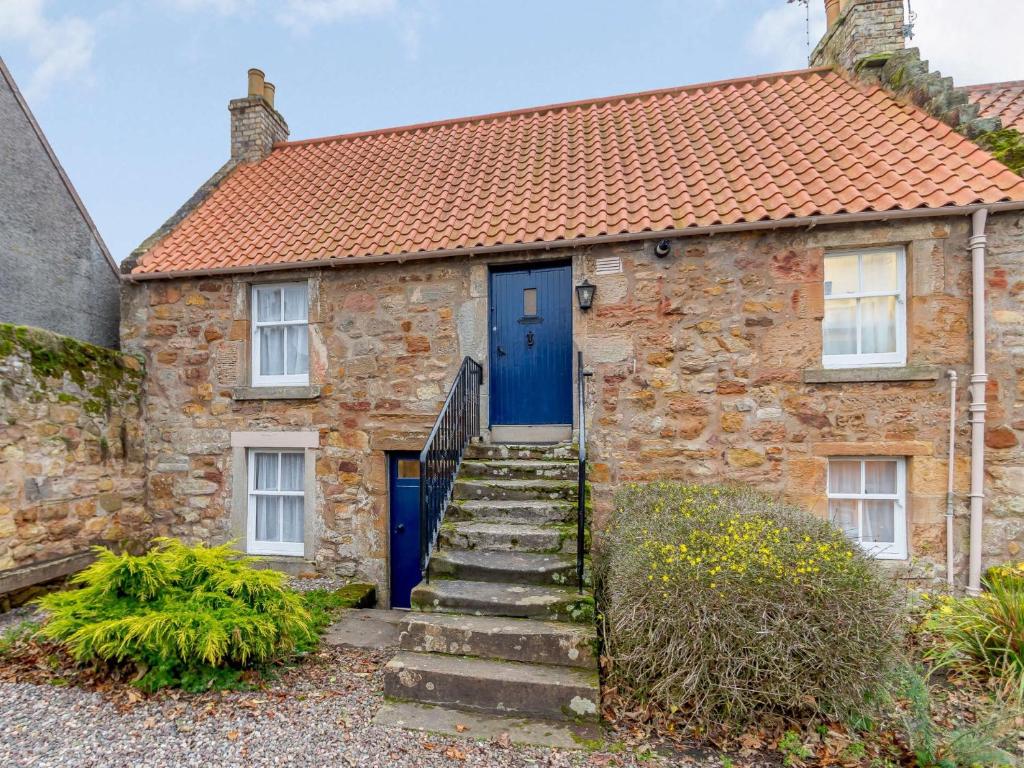 a stone house with a blue door and stairs at 2 Bed in Crail CA006 in Crail