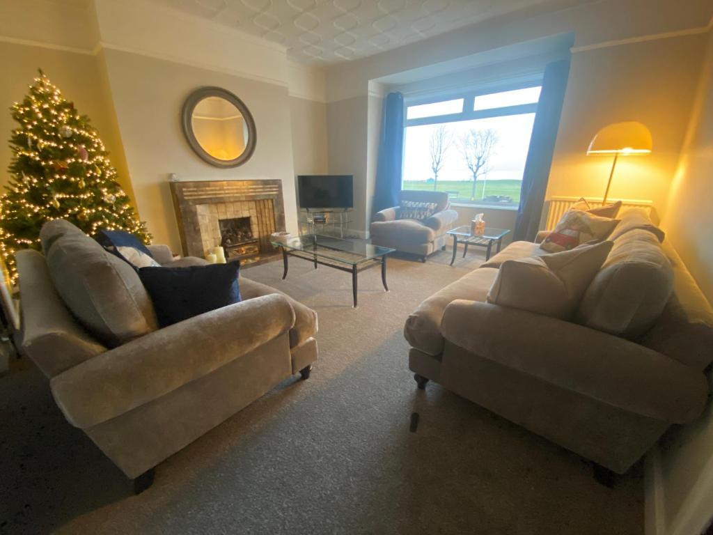 a living room with a christmas tree and two couches at Amazing views across the Moray Firth, Private Suntrap Patio, 300m from the Beach, off street parking! in Nairn