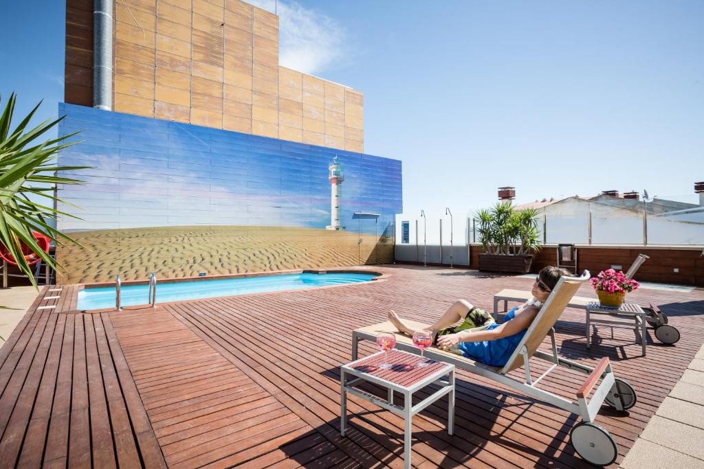 a woman sitting in a chair next to a pool at Hotel Rull in Deltebre