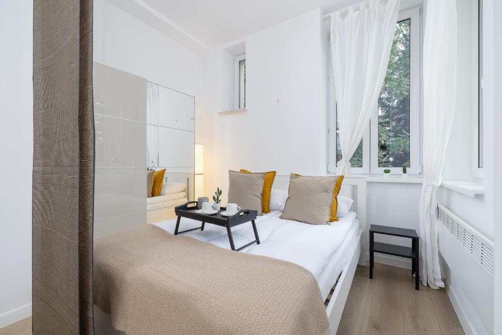 Dormitorio blanco con cama y mesa en Mickiewicza Charming Studio for 2 Guests by Renters, en Cracovia