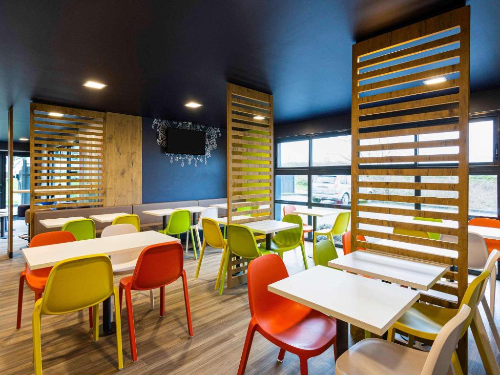 - un restaurant avec des tables et des chaises colorées dans une chambre dans l'établissement ibis budget Angoulême Nord, à Champniers