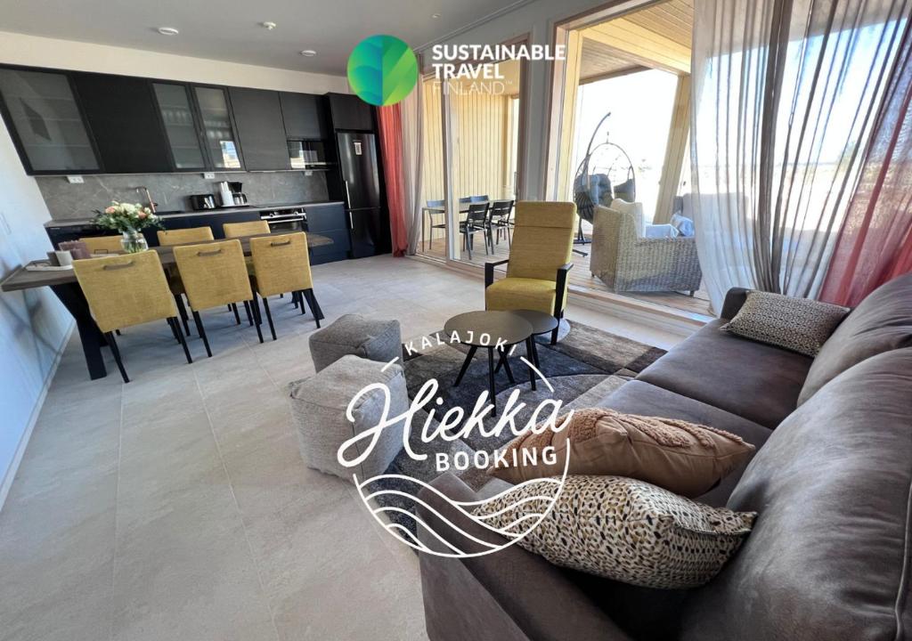 a living room with a brown couch and a kitchen borrowing at Villa Resort Apartments by Hiekka Booking in Kalajoki