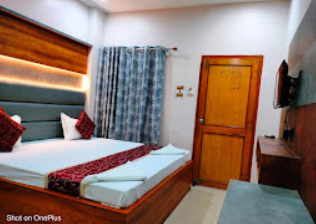 - une chambre avec un lit, une télévision et une porte dans l'établissement Hotel City Park Guwahati, à Guwahati