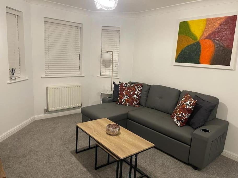 uma sala de estar com um sofá e uma mesa em Jdb Romford Apt - Cosy 2 Bedroom with parking em Harold Wood