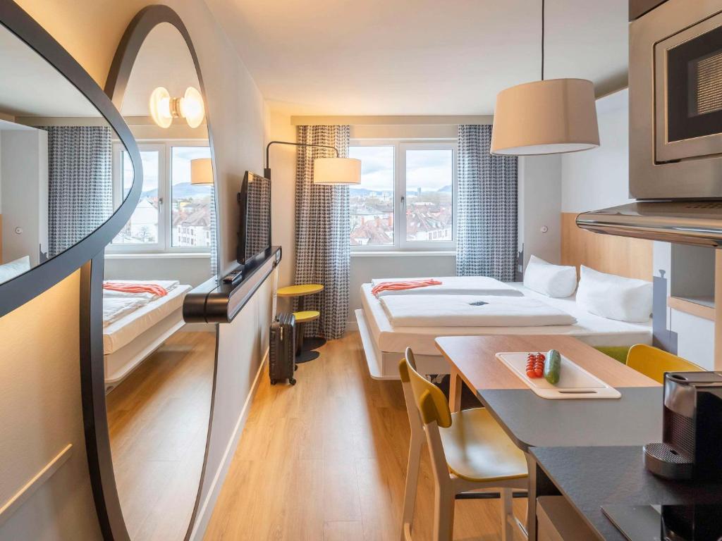 ein Hotelzimmer mit einem Bett und einem Esstisch in der Unterkunft Aparthotel Adagio Access Freiburg in Freiburg im Breisgau