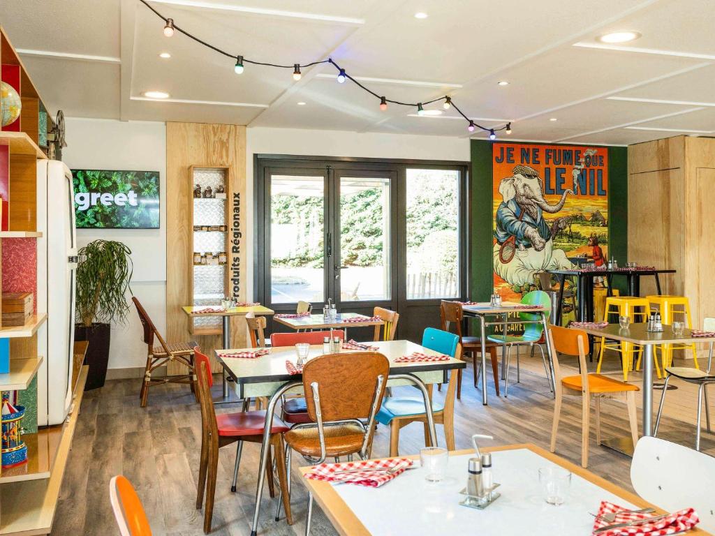 une salle à manger avec des tables et des chaises dans un restaurant dans l'établissement greet hôtel restaurant Angoulême Ouest, à Saint-Yrieix-sur-Charente