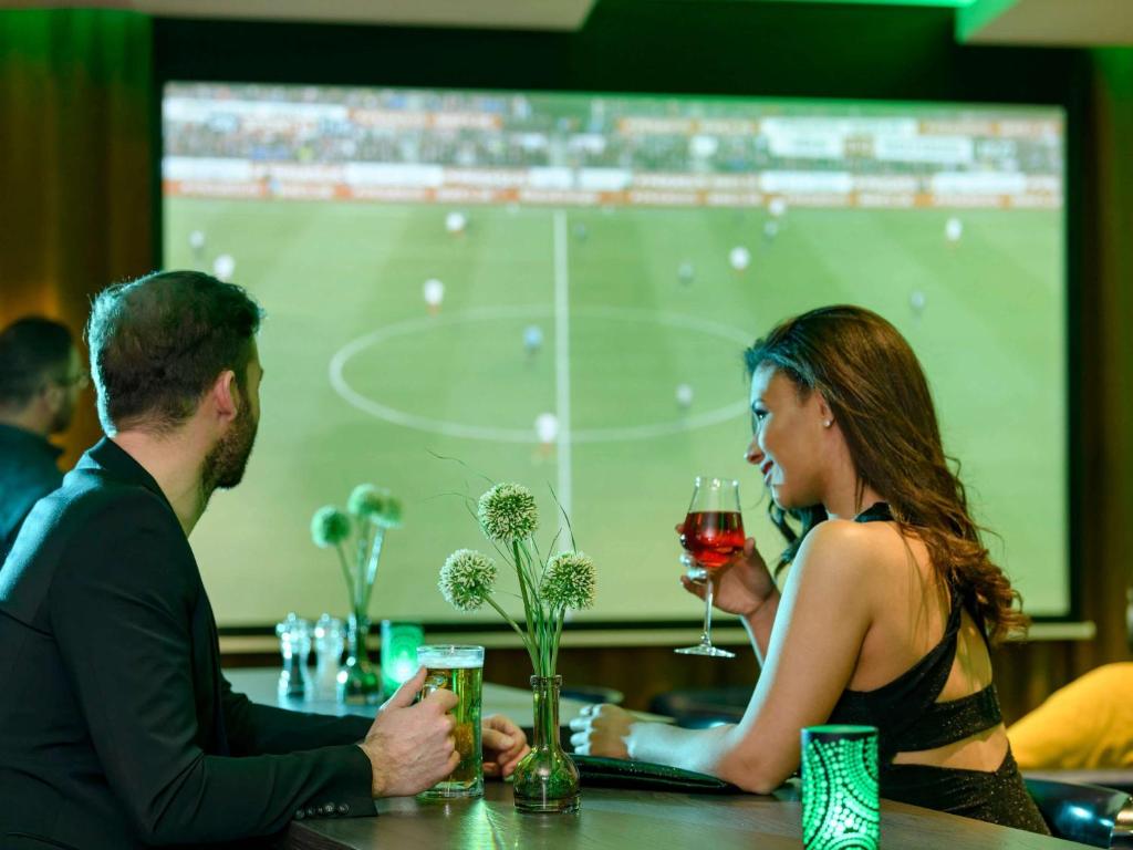 a man and a woman sitting at a bar with wine glasses at ibis Styles Kiel City in Kiel