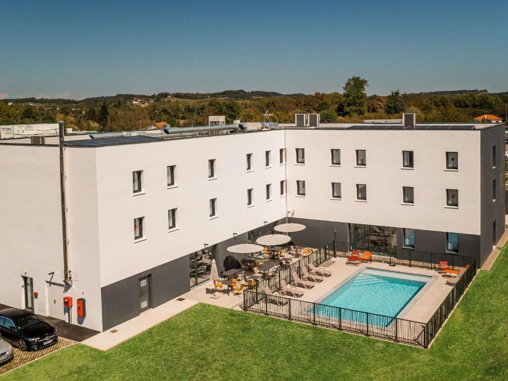 an aerial view of a white building with a swimming pool at Greet Hôtel Orthez Bearn in Orthez