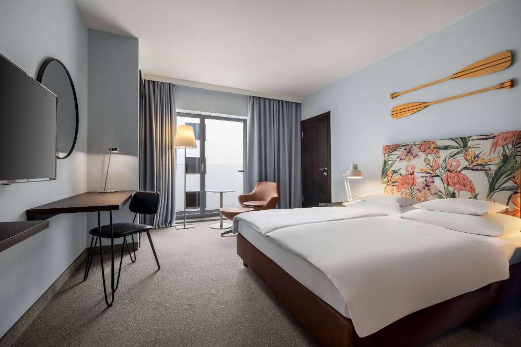 a hotel room with a large bed and a desk at Vienna House by Wyndham Andel's Cracow in Kraków