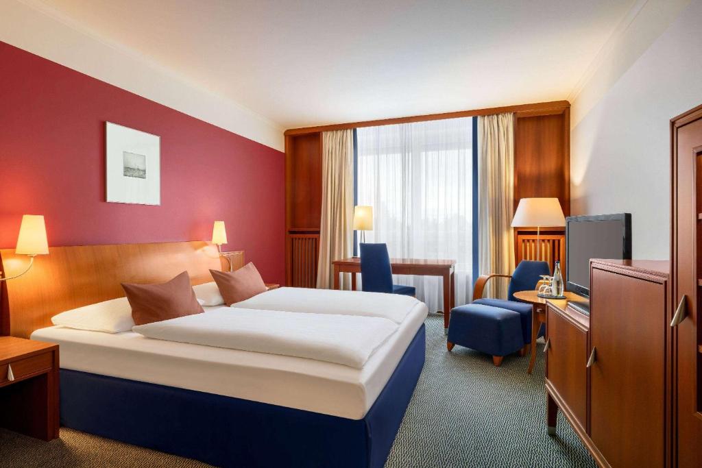 una camera d'albergo con letto e scrivania di Vienna House by Wyndham Sonne Rostock a Rostock