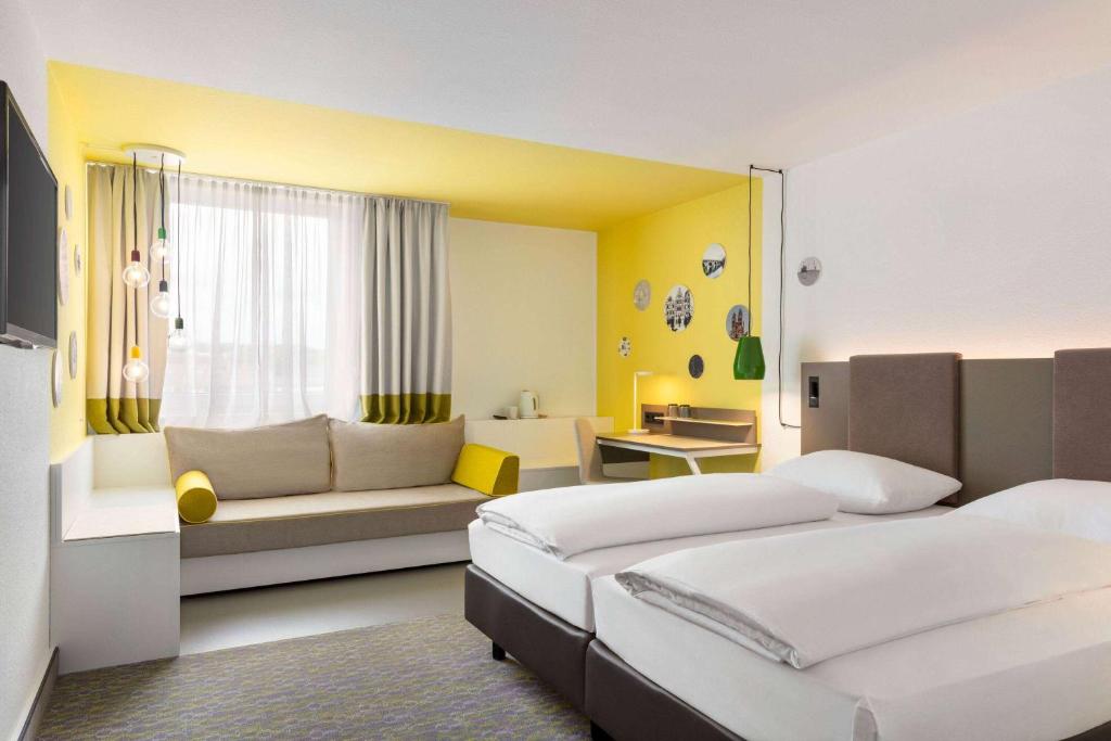 Habitación de hotel con 2 camas y sofá en Vienna House Easy by Wyndham Limburg, en Limburg an der Lahn