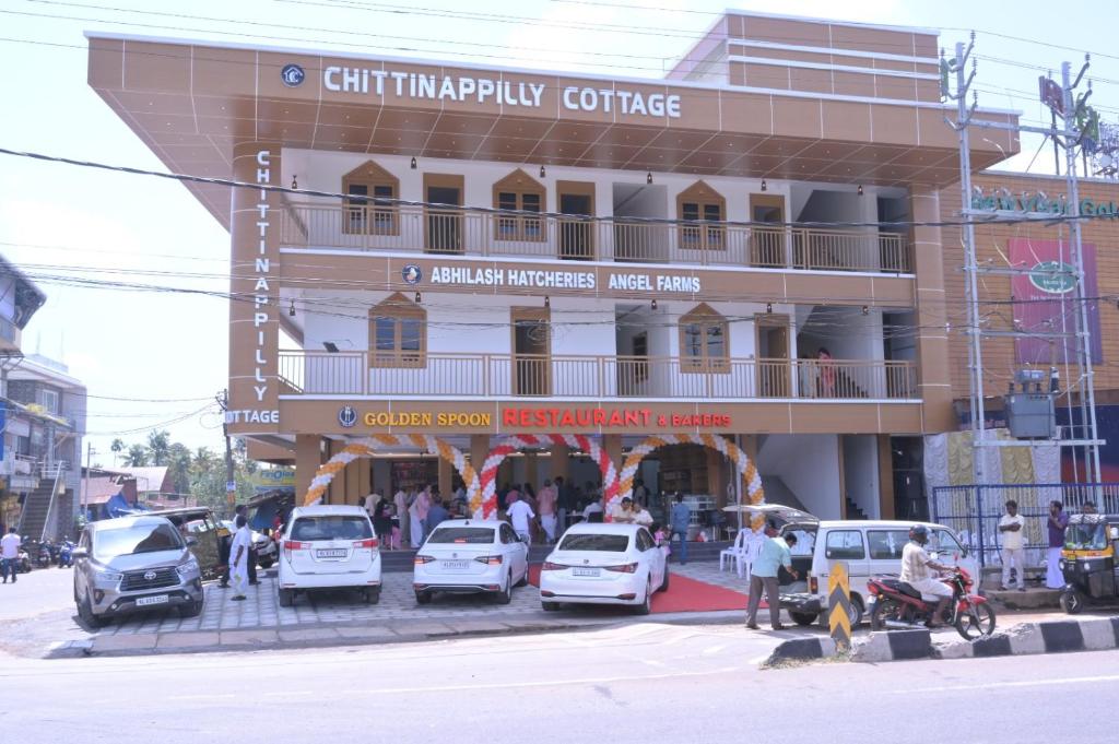 Chittinappilly Cottage في أنغمالي: مبنى فيه سيارات تقف امامه