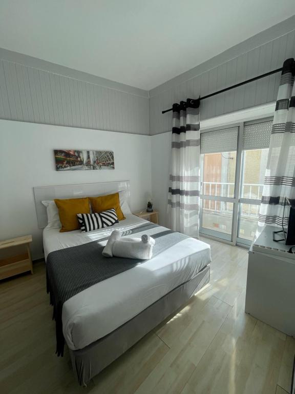 a bedroom with a large white bed with yellow pillows at West Coast Peniche in Peniche