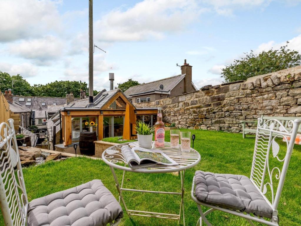 a garden with a table and chairs and a stone wall at 2 Bed in Rothbury 83597 in Rothbury