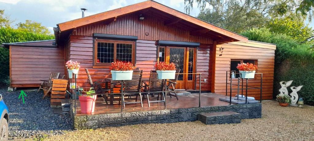 een kleine houten hut met stoelen en een veranda bij Chalet Nutons in Somme-Leuze