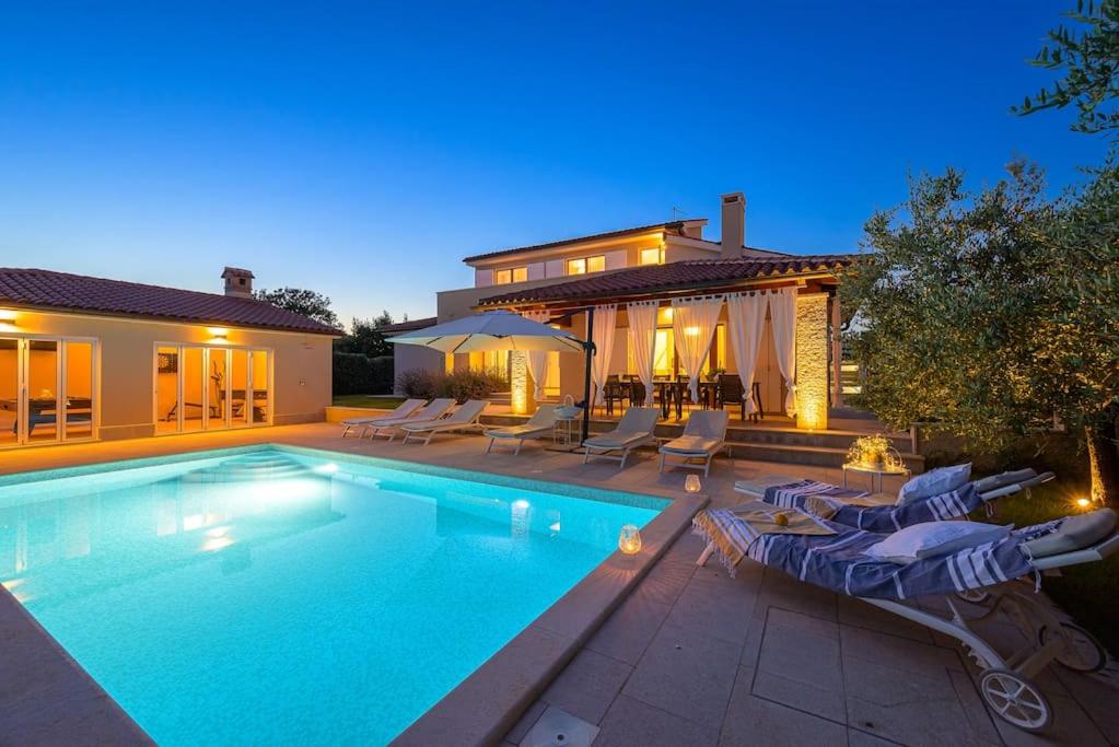 a swimming pool with chairs and a house at Villa Lana by IstriaLux in Vodnjan