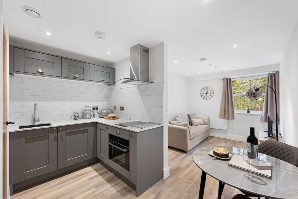 a kitchen with gray cabinets and a table and a couch at Cavendish 37 in Tideswell