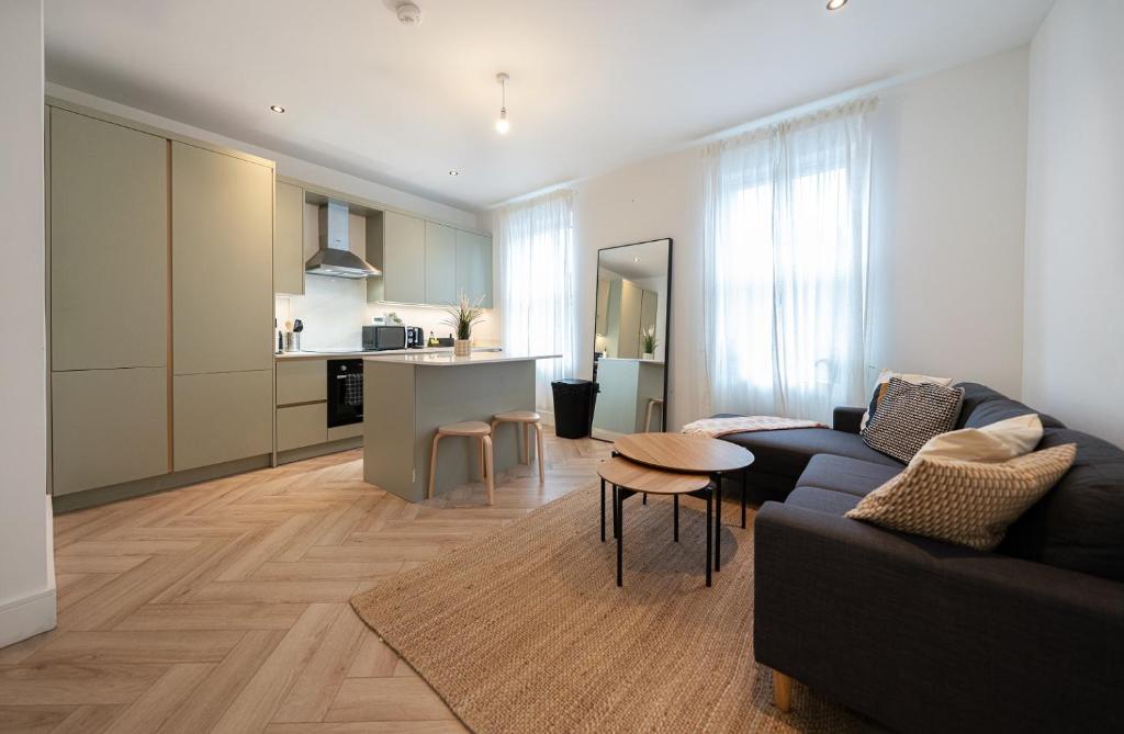 uma sala de estar com um sofá preto e uma cozinha em The Battersea Scenery - Elegant 2BDR Flat em Londres