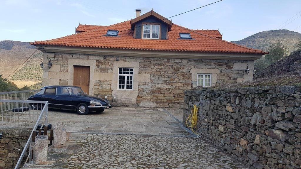 a car parked in front of a stone house at Casa do Riacho - Douro in Armamar