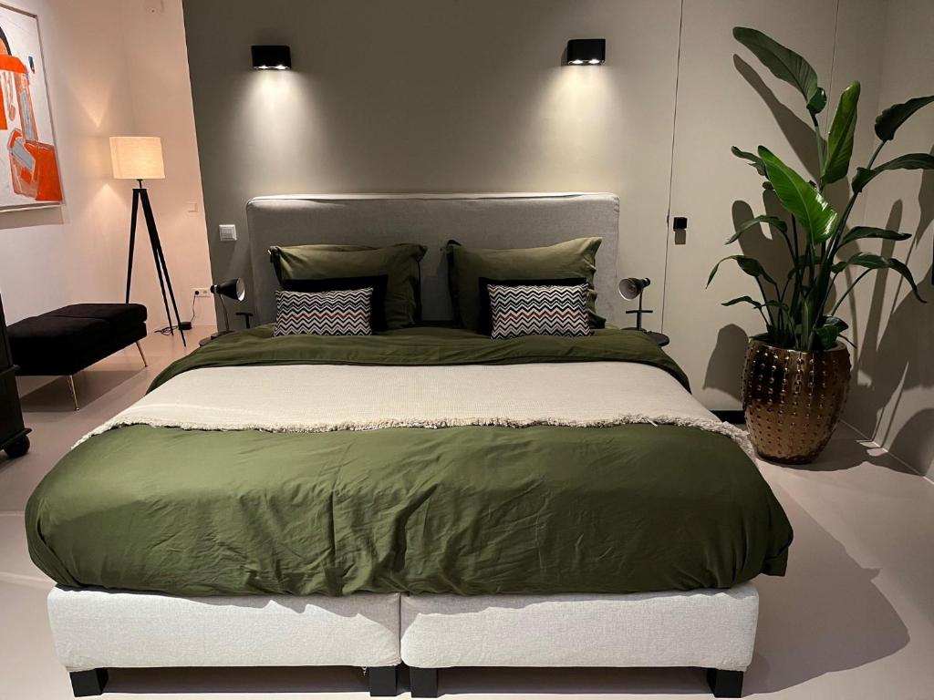 a bedroom with a large bed with a green comforter at B&B Urban Oasis in Amsterdam