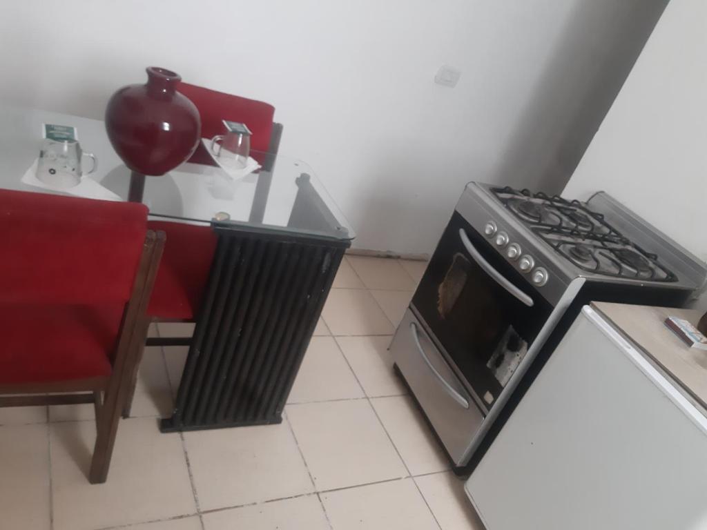 Hostel positivo في بوينس آيرس: مطبخ مع موقد وكرسي احمر