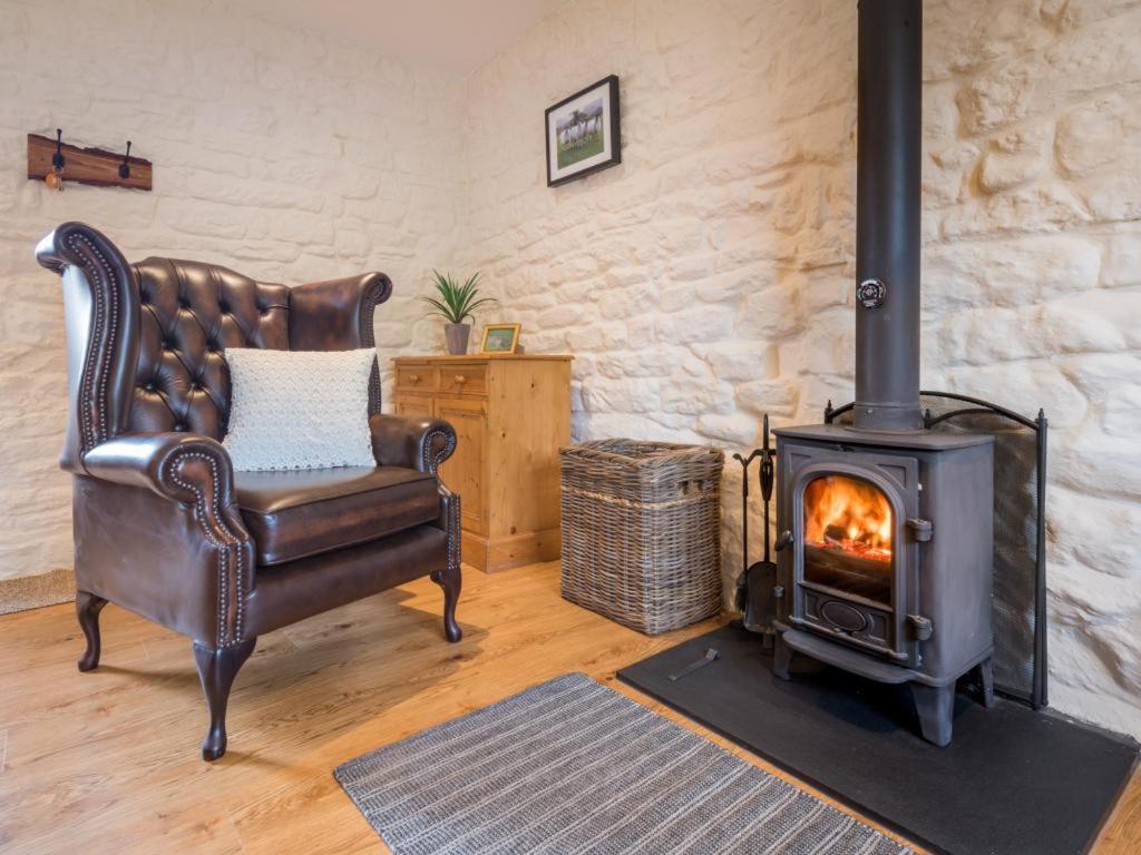 a leather chair in a living room with a wood stove at 1 Bed in Eden Valley SZ237 in Kirkoswald
