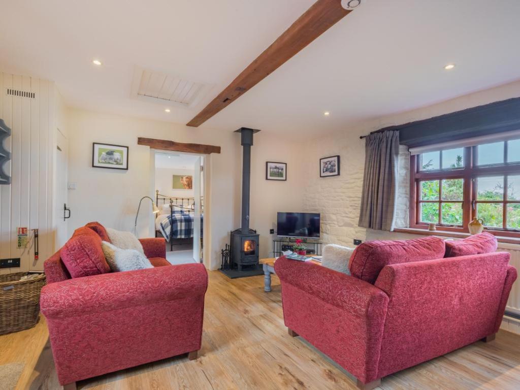 uma sala de estar com duas cadeiras vermelhas e uma lareira em 2 Bed in Eden Valley SZ269 em Kirkoswald