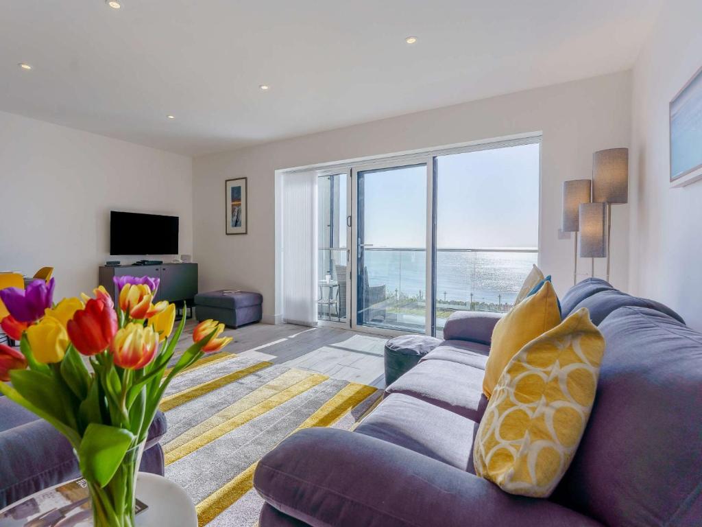 a living room with a blue couch and flowers at 2 bed in Sandown 87079 in Sandown