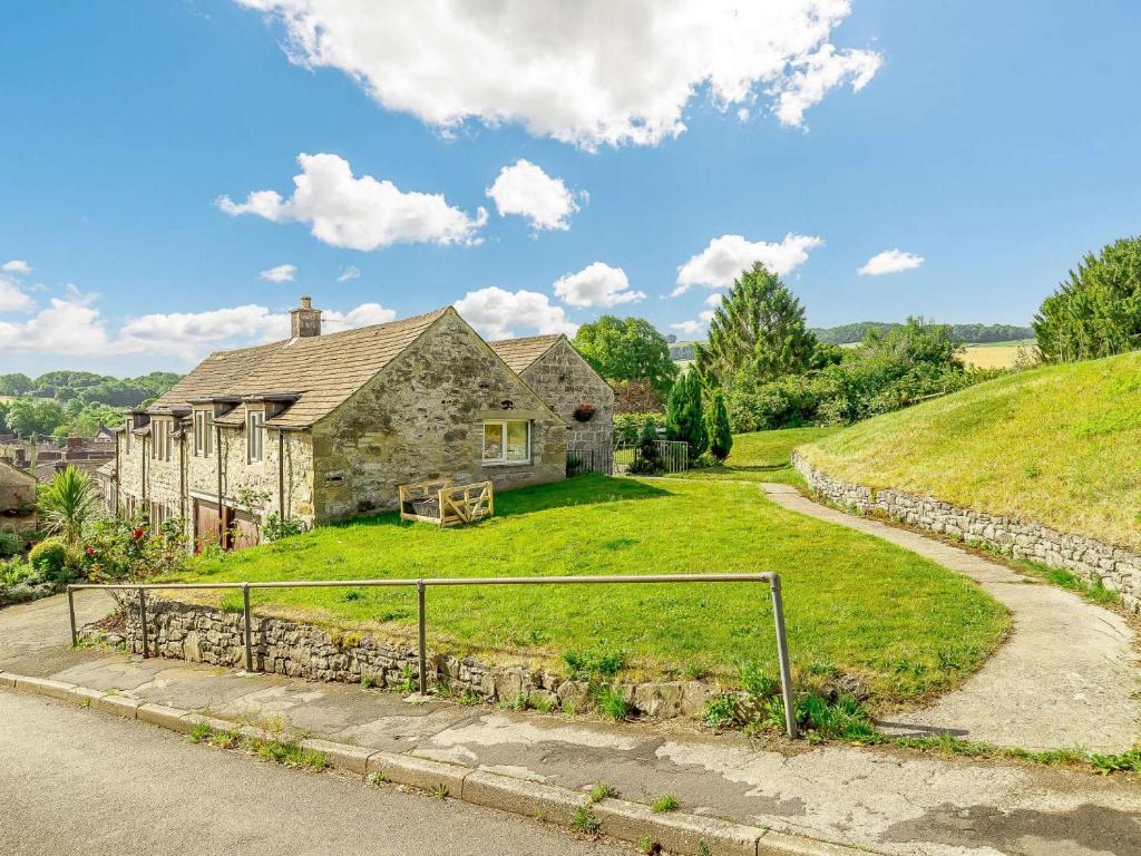 an old stone house on a hill with a road at 1 Bed in Ashford-in-the-Water 87471 in Great Longstone