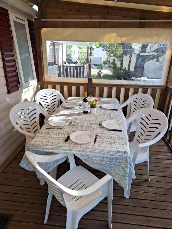 einen Tisch auf einer Veranda mit weißen Stühlen und einem Fenster in der Unterkunft Mobile home Chic in Canet-en-Roussillon