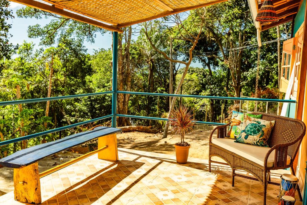 a screened in porch with a bench and a chair at Casa Papaya in Santa Cruz Cabrália