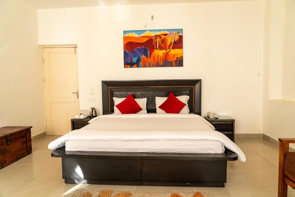 a bedroom with a large bed with red pillows at Aestus Adventure and Wellness Centre in Kasauli