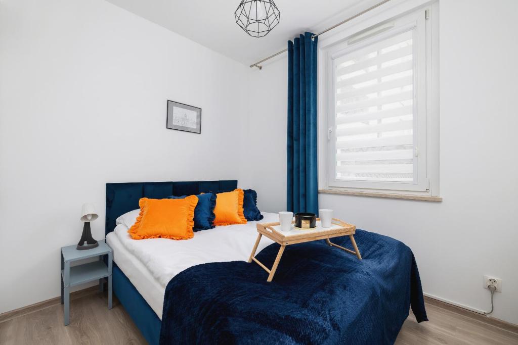 a bedroom with a bed with blue and orange pillows at Cracow Royal Blue Apartment Avia Estate by Renters in Kraków