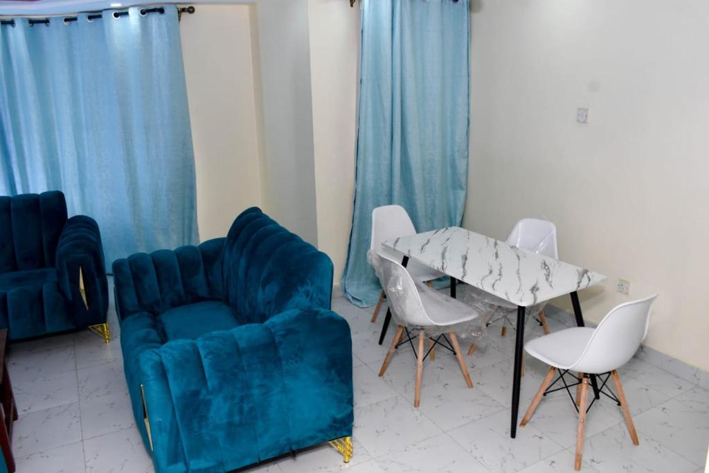 a living room with a blue couch and chairs and a table at Madaraka - Nairobi West in Nairobi