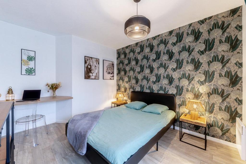 a bedroom with a bed and a desk with a laptop at Charmant et fonctionnel in Talence