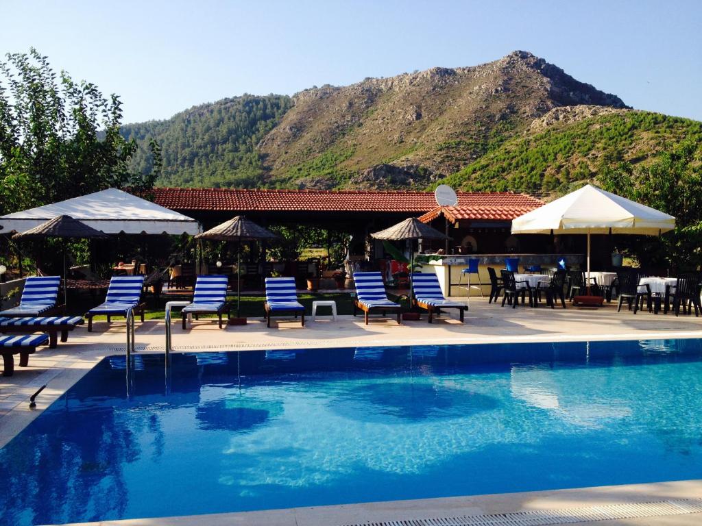 a swimming pool with chairs and umbrellas and a restaurant at Erol Motel in Orhaniye