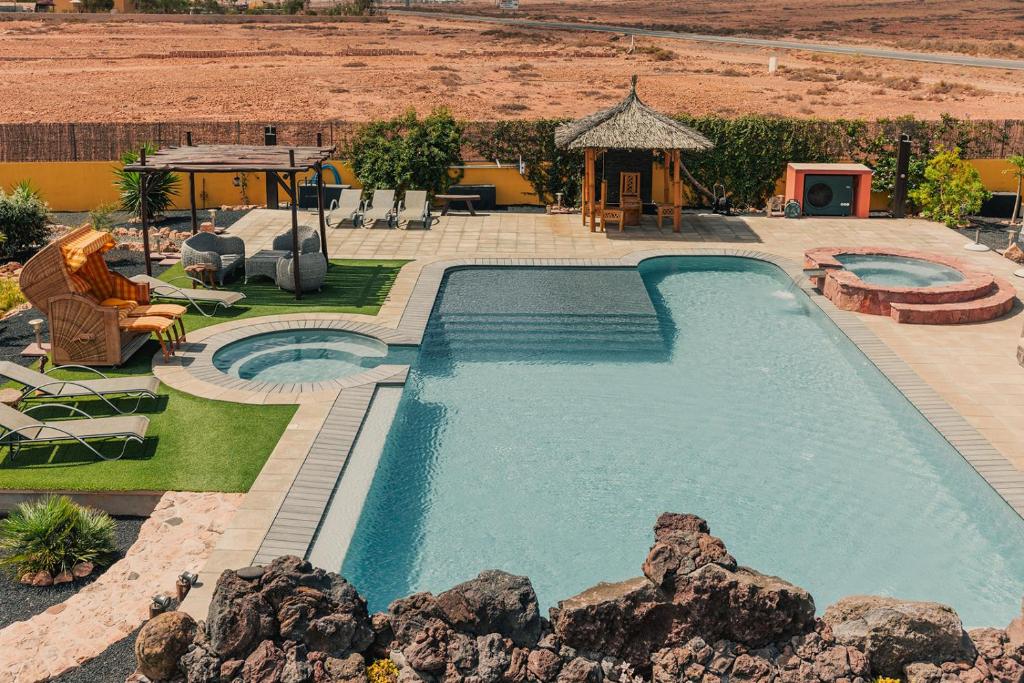 a swimming pool in a yard with chairs at Shangri-La Fuerteventura in Tefía