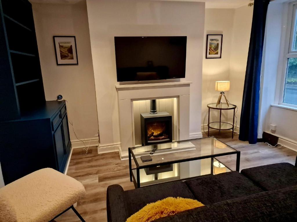 a living room with a fireplace and a couch and a tv at Over Torrs Cottage in New Mills