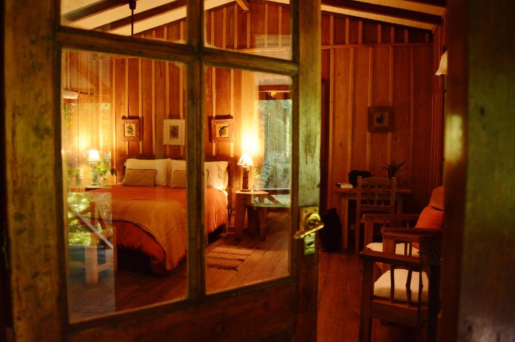 um quarto com uma cama e uma porta de vidro em Margay - Reserva Natural y Lodge de Selva em El Soberbio