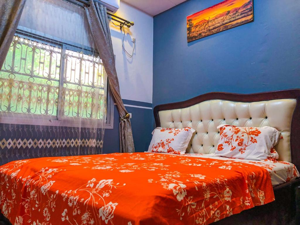 1 dormitorio con 1 cama con manta naranja y ventana en Chic Appart au cœur de Douala Bonamoussadi, en Douala