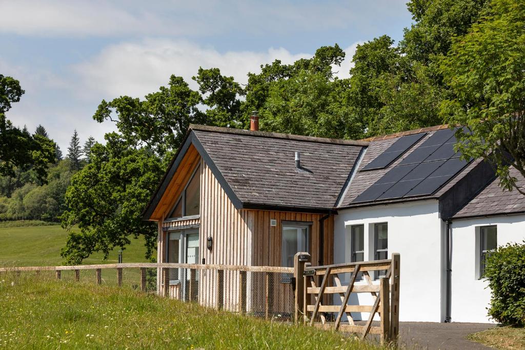 una pequeña casa con paneles solares en el techo en Slatehouse Cottage, Drumlanrig en Thornhill