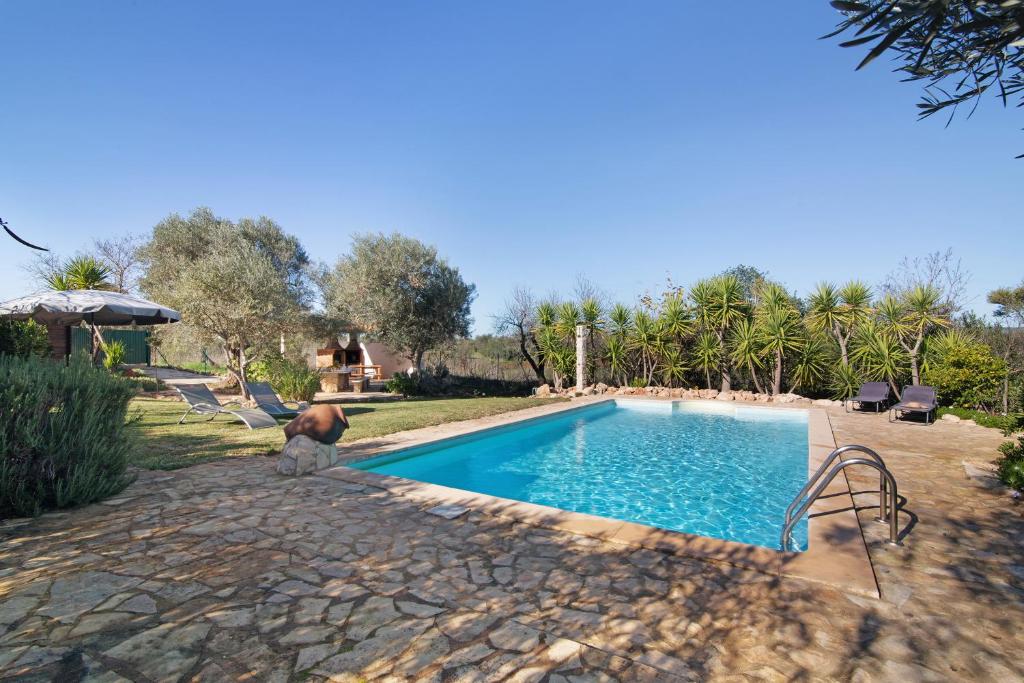 een zwembad in een tuin met bomen en een huis bij Casa Palma in Paderne